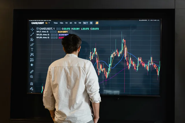 Back view of a trader analyzing cryptocurrency data on a monitor indoors. Sygnały wczesnego ostrzegania na rynku: jak odróżnić szum od zmiany